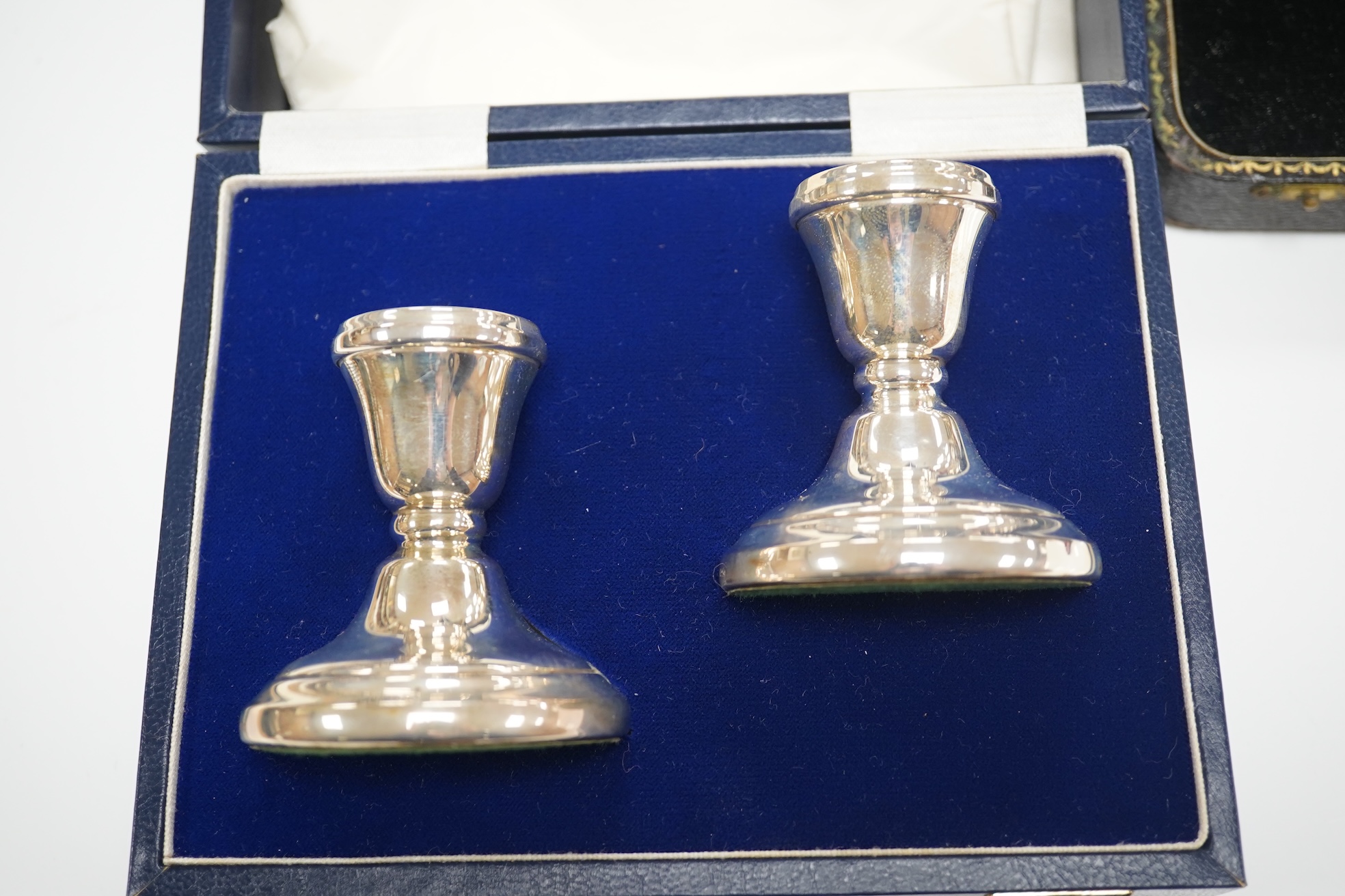 A set of six silver grapefruit spoons, Cooper Brothers & Sons, Sheffield, 1936, a modern pair of silver mounted dwarf candlesticks, a silver egg cup and spoon and a set of six silver gilt and enamelled coffee spoons, all